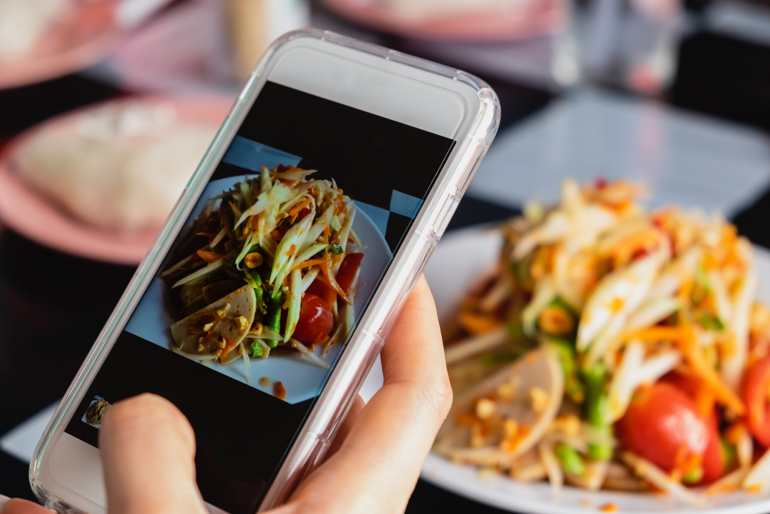Woman taking a photo of thai green papaya salad with smartphone Google Review 5 Stars